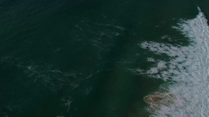aerial footage of the English coast with rocky cliffs and breaking waves, camera panning up from water