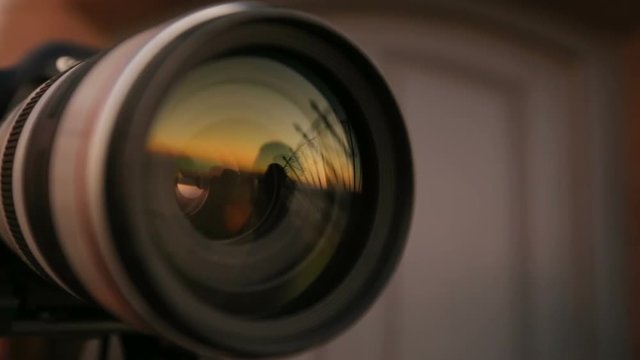 Man posing against sunset, reflection in camera lens, journalist at work, hobby