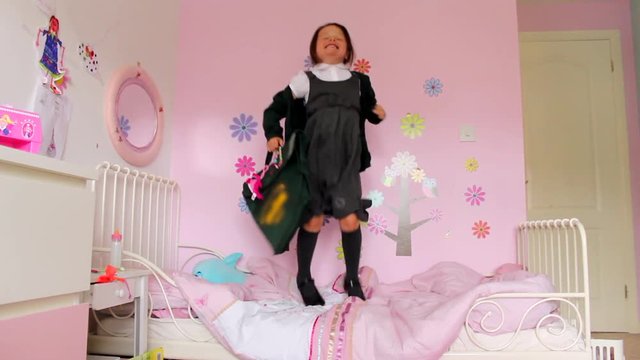 Children jumping on bed with school uniform getting ready for first day back at school
