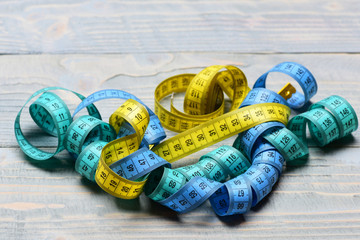 Handful of measuring tapes in different colors: yellow, blue, cyan