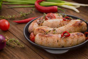 Grilled sausages in frying pan. Wooden background. Top view. Close-up
