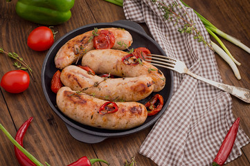 Grilled sausages in frying pan. Wooden background. Top view. Close-up