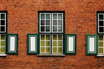 Fototapeta na wymiar Fragment of a building with windows of an ancient palace of red brick