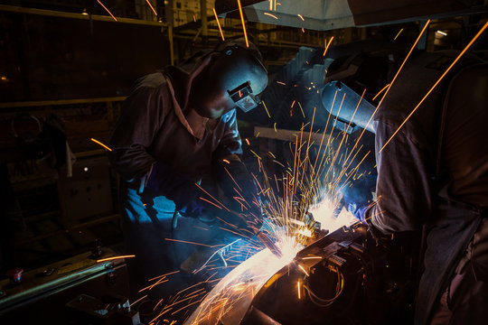 Team welders are welding in factory