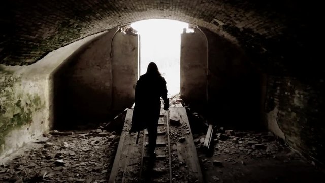 Bearded man dressed in assassin's costume is exiting the ruined fortress.