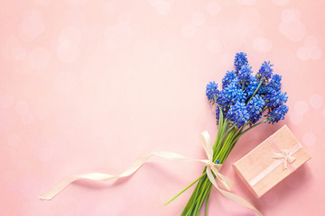 Bouquet of blue muscari flowers with gift box on pink background. Place for text. Top view
