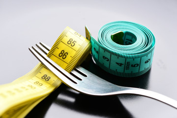 Roll of green measuring tape next to metal fork