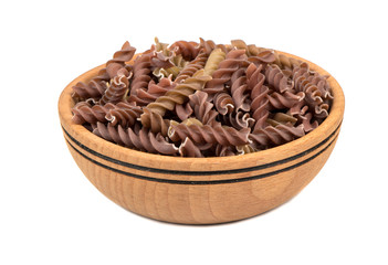 Wooden bowl filled with raw pasta fusilli on white background