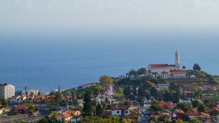 Madeira - View to church Sao Martinho from Miradouro Pico de Boloces with blue ocean behind