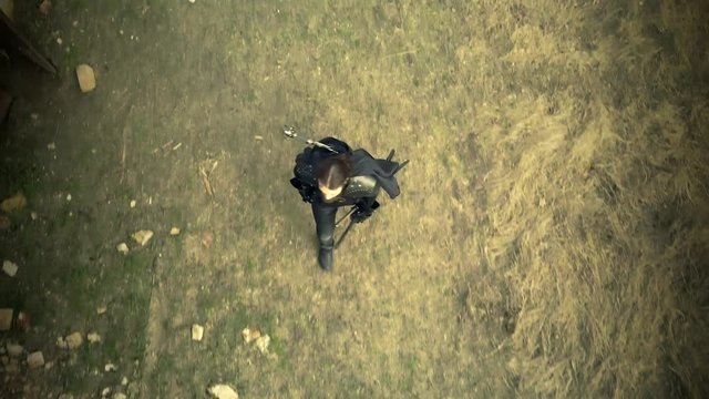 Top view from drone on man dressed in assassin's costume training with a sword on the field.