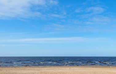 Fototapeta na wymiar Jurmala (Riga), Latvia - April 27, 2017: Sea coast line with blue sky on horizon. Landscape in sunny day