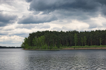 Gray storm clouds over the forest and lake. Pisochne ozero. Volyn region. Ukraine
