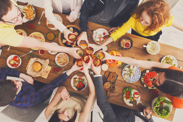 People say cheers clink glasses at festive table dinner party