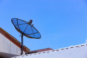 Satellite dish on the house roof communication technology network with blue sky
