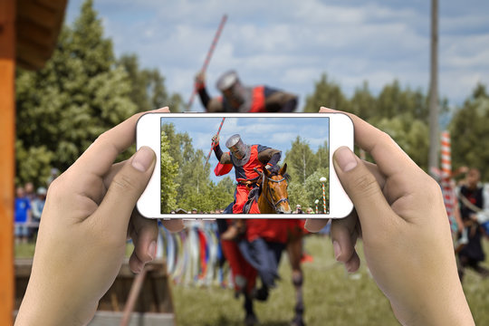 Hands taking photo of knight on horse by smartphone
