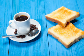 Breakfast with coffee, toasts, butter and jam on white wooden background