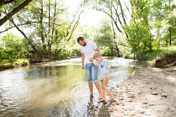 Young father with little boy at the river, sunny spring day.