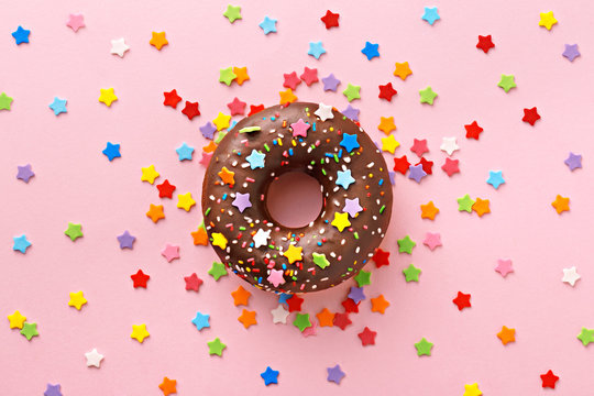 Donut decorated with sweet stars on a pink background. Celebration concept. Top view
