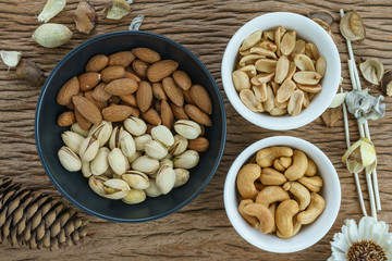 appetizer roasted delicious salt pistachios, cashew nuts, peanuts and almonds food in black bowl on wooden table background