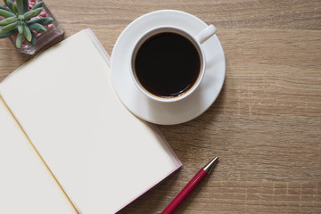 Americano coffee, note books, and pen are placed on a brown table wooden workspace