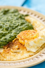 Cooked spinach served with fried eggs and slice of bread