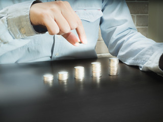 Close up hand putting money coins stack in saving money or growing business concept