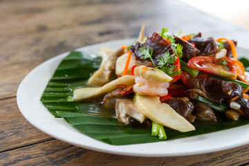 restaurant food - roasted potatoes with vegetables and mushrooms, parsley at light brown wooden background.