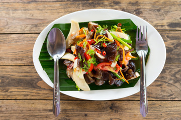 restaurant food - roasted potatoes with vegetables and mushrooms, parsley at light brown wooden background. Top view.