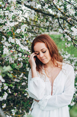 Red-haired girl with freckles near the apple tree