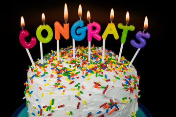 congrats candles on layered cake with colorful sprinkles