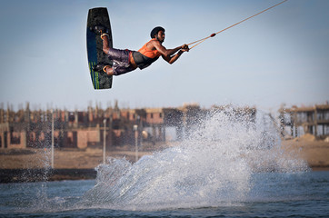Wakeboarding sportsman jumping high wake boarding raley trick with huge water splash in the...