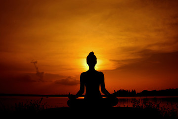 Young woman in a meditating yoga the beautiful sunset
