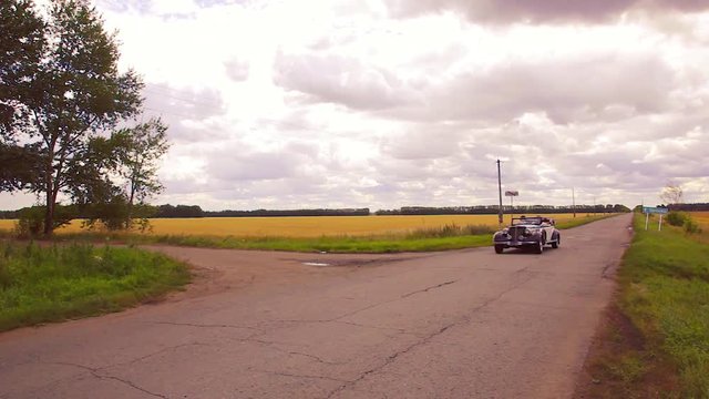Retro car rides on the road through the field