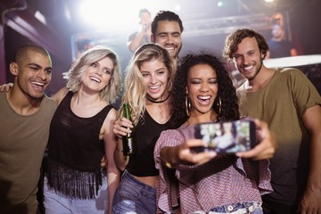 Cheerful friends talking selfie at nightclub