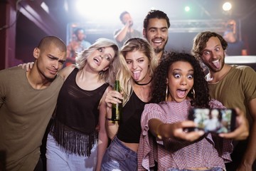Cheerful young friends talking selfie at nightclub