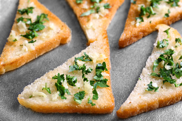 Tasty bread slices with garlic and herbs on metal background, closeup