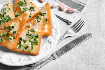 Tasty bread slices with garlic and herbs on plate