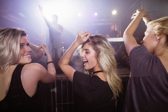 Happy Female Friends Dancing At Nightclub