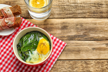 Delicious eggs Florentine in bowl and napkin on wooden table