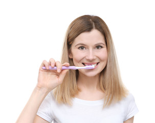 Portrait of beautiful young woman brushing teeth on white background