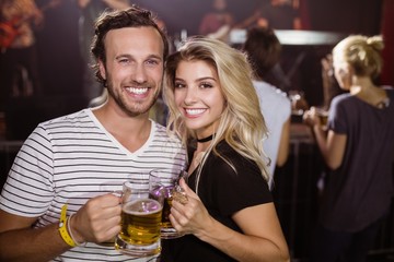 Portrait of smiling young friends holding beer mugs