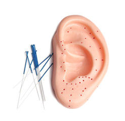Needles for acupuncture and plastic mockup of human ear on white background