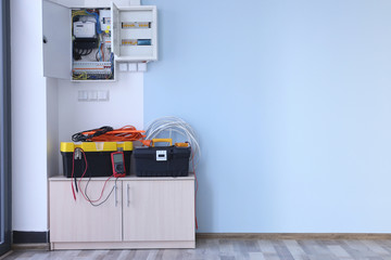 Distribution board with wires and tools on table in light room
