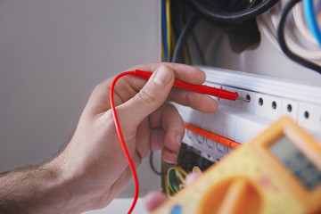 Young electrician measuring voltage in distribution board