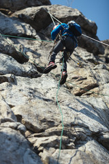 Climber climbs up the rope in the mountains.