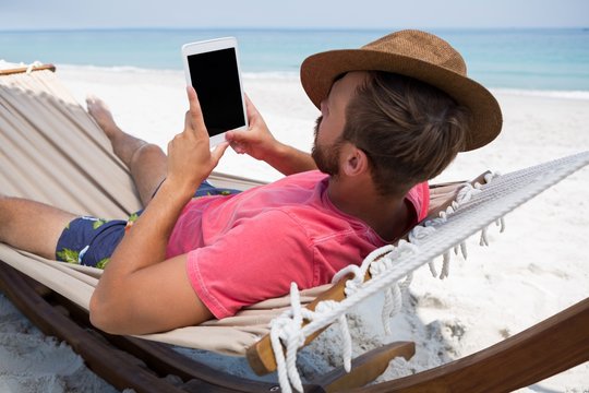 Man using digital tablet while relaxing in hammock