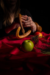 A girl dressed in black is holding a snake above a table with apples