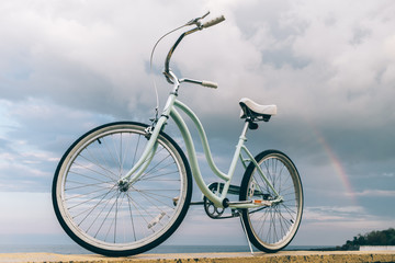 Fototapeta na wymiar Vintage women's bike on the background of the sea and a rainbow