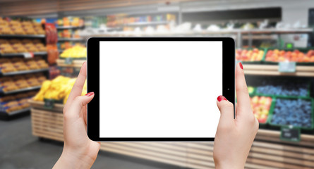 Girl holding tablet with empty screen in horizontal position at grocery store