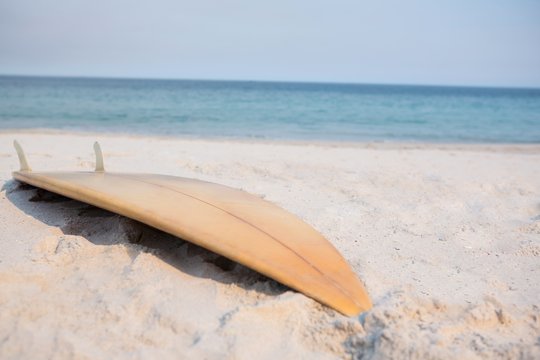 Wooden surfboard on sand at beach